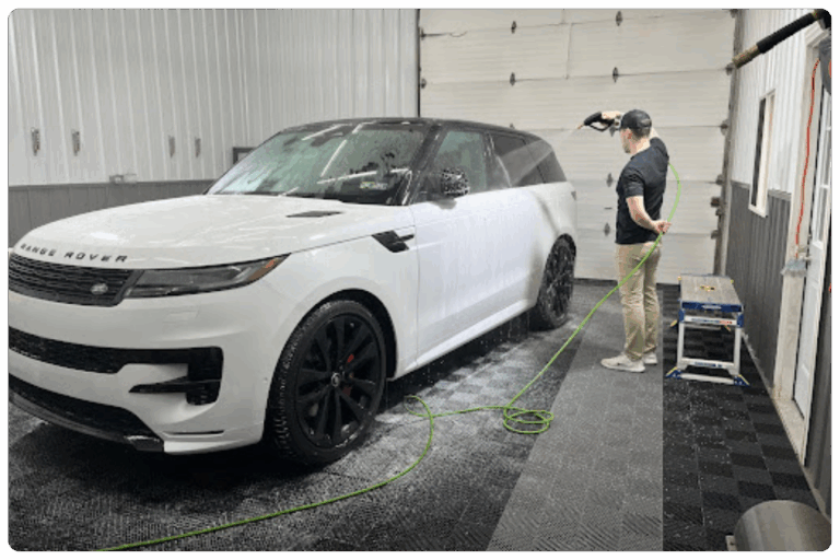 Professional paint correction specialist preps a vehicle with a decontamination wash.