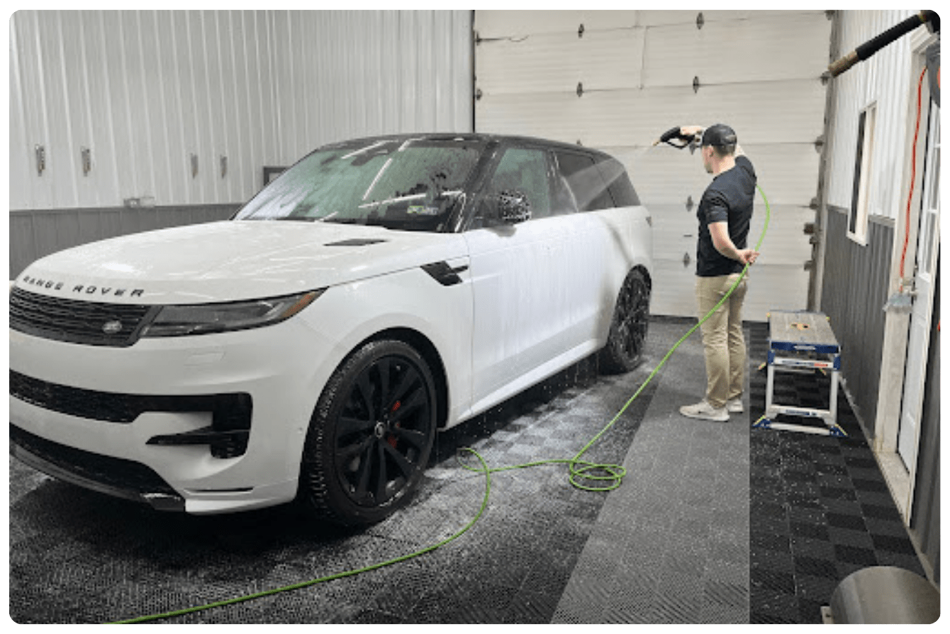 Professional paint correction specialist preps a vehicle with a decontamination wash.